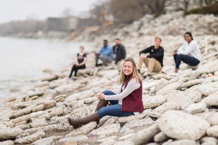 Students gather on the rocks by the lakeshore